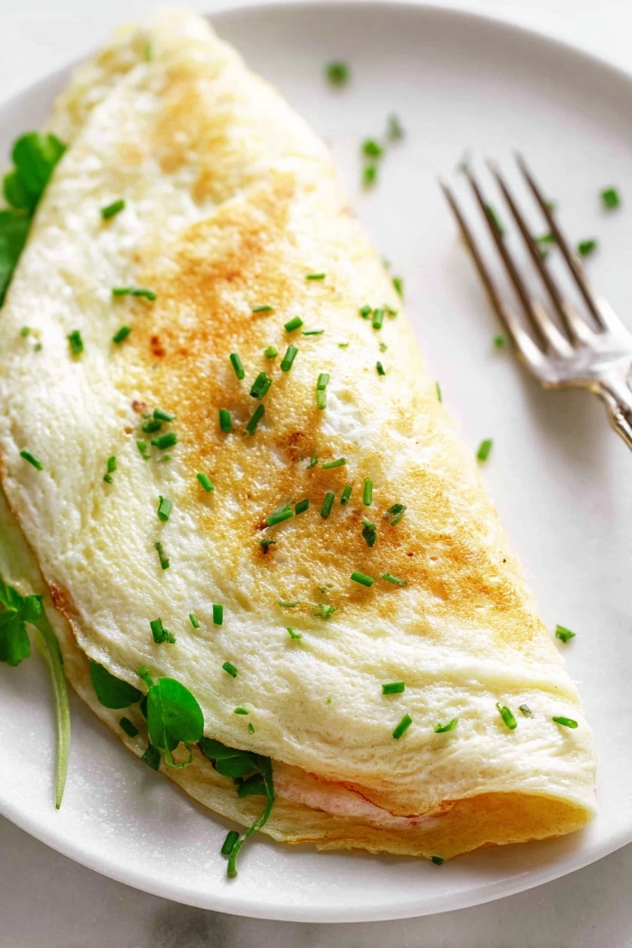 Fluffy Egg White Omelette with Asparagus, Prosciutto, and Pecorino, healthy egg white omelette, asparagus breakfast recipe, prosciutto egg dish, pecorino cheese omelette - A close-up view of a folded omelette sitting on a white plate over a white marbled surface, showing a soft, slightly browned, creamy white outer egg layer sprinkled with finely chopped green herbs on top; inside, there are visible layers of melted light cheese, pink ham pieces, and green bell pepper strips, all slightly oozing out along the fold; next to the omelette on the plate is a metal fork with an ornate handle, and in the blurry background, there is a red roasted pepper. photo taken with an iphone --ar 2:3 --v 7